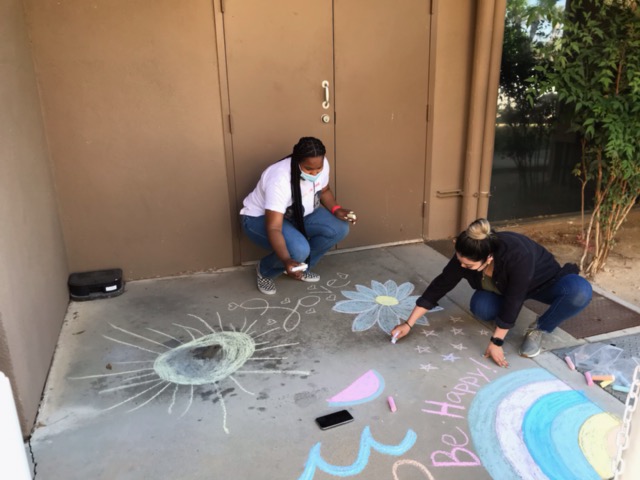 2 women drawing on concrete with chalk