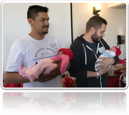 new fathers holding newborn babies wearing red hats